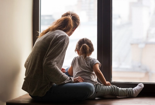 Une maman et sa petite fille regardant par la fenêtre
